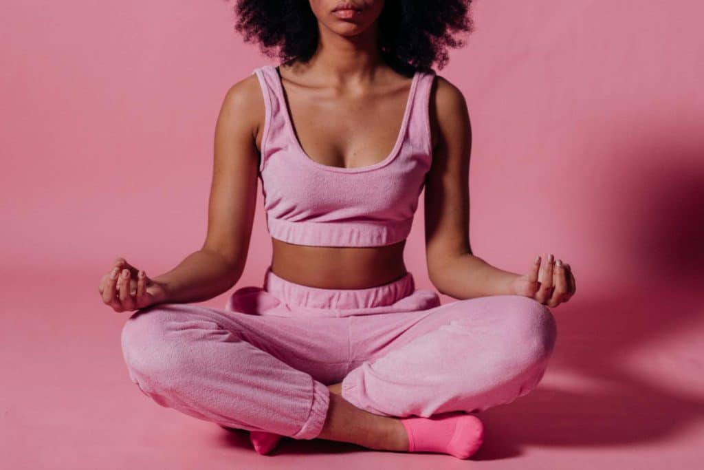 75 hard challenge with woman in pink crop top and jogging pants practicing yoga