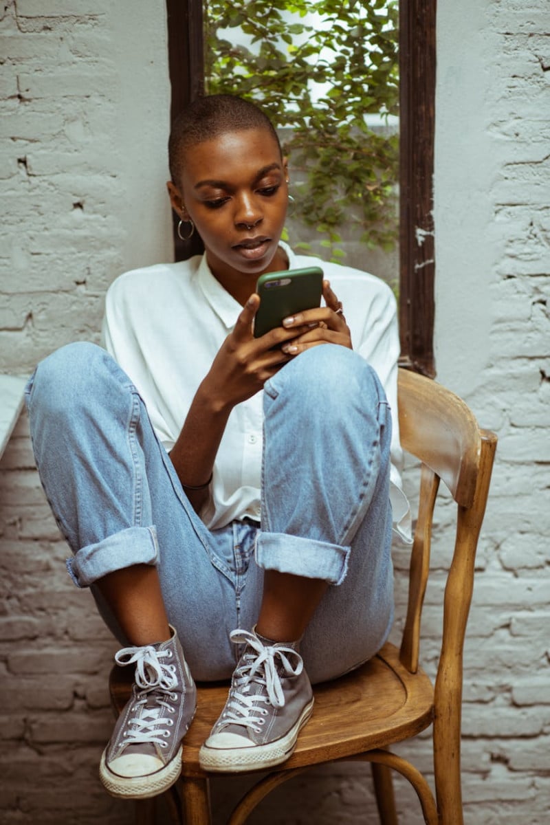 concentrated woman in jeans chatting via smartphone unconsciously spending